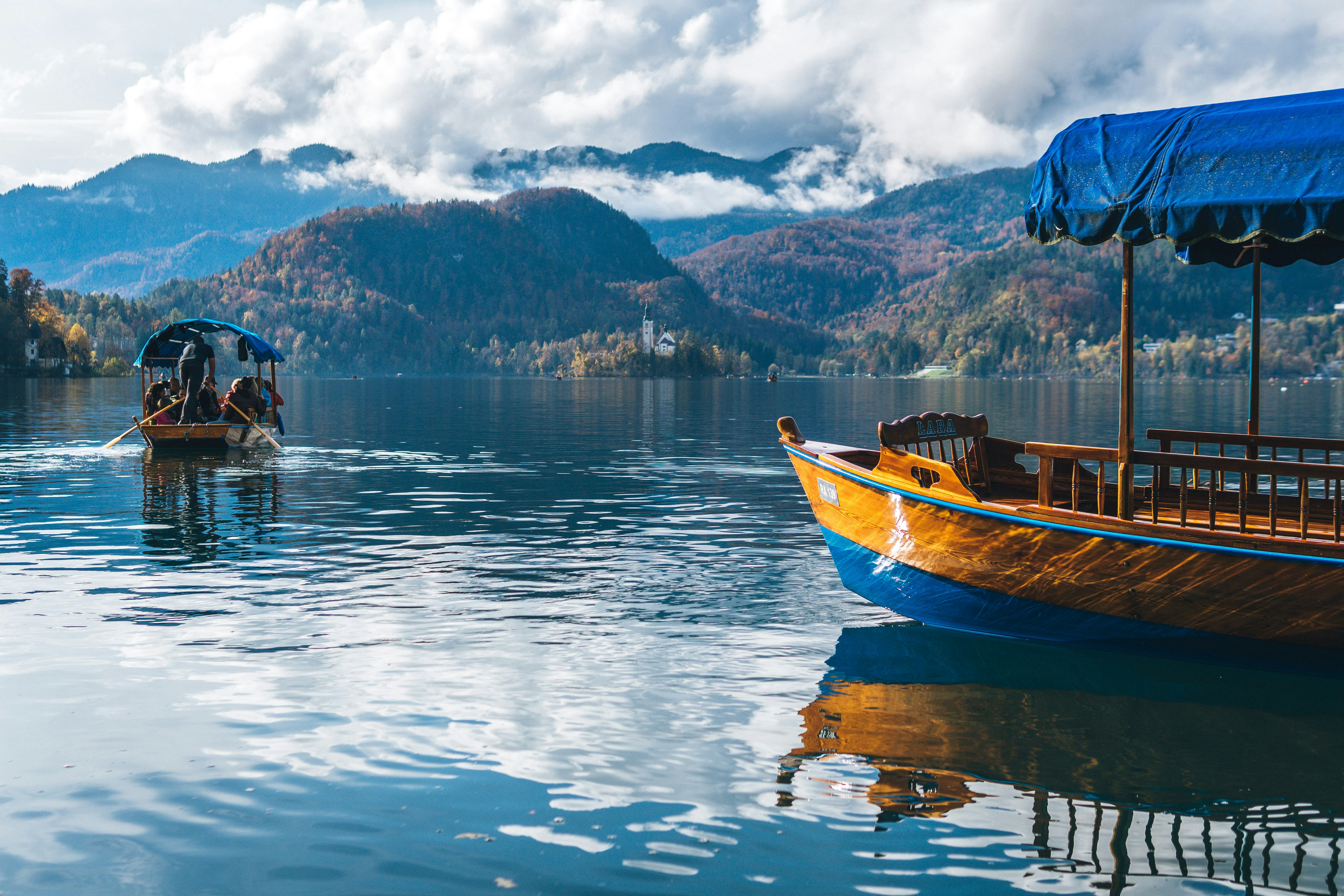 brown and white boat on water near mountain during daytime